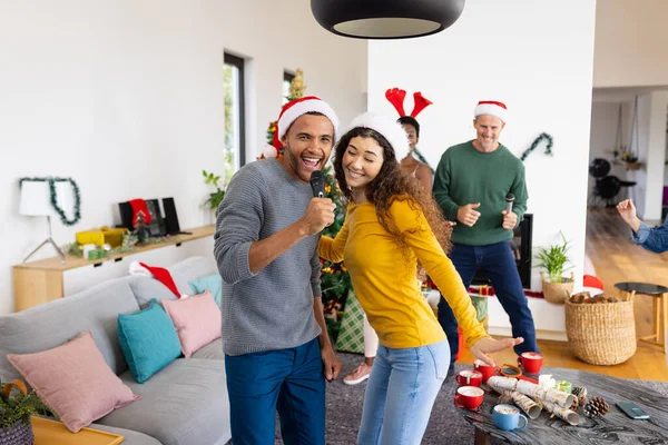 照片上 一对快乐的 多样化的夫妇和朋友在家里唱卡拉Ok庆祝圣诞节 圣诞节 庆祝活动 包容和生活方式概念 — 图库照片