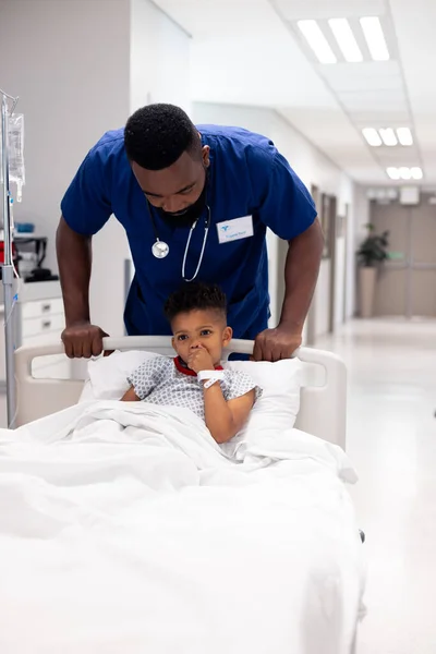 Вертикаль Африканского Врача Американца Который Толкает Мальчика Больничную Койку Коридоре — стоковое фото
