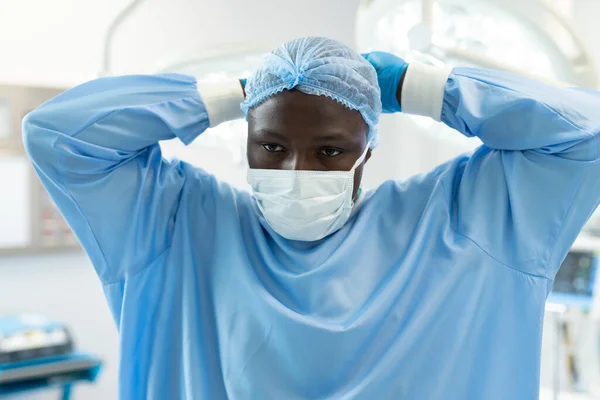手術用ガウンを着たアフリカ系アメリカ人男性外科医と手術室のマスクにネクタイキャップ 医療サービス — ストック写真