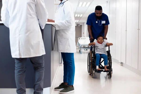 Hastane Koridorunda Tekerlekli Sandalyedeki Hasta Çocuğu Iten Afrikalı Amerikalı Erkek — Stok fotoğraf
