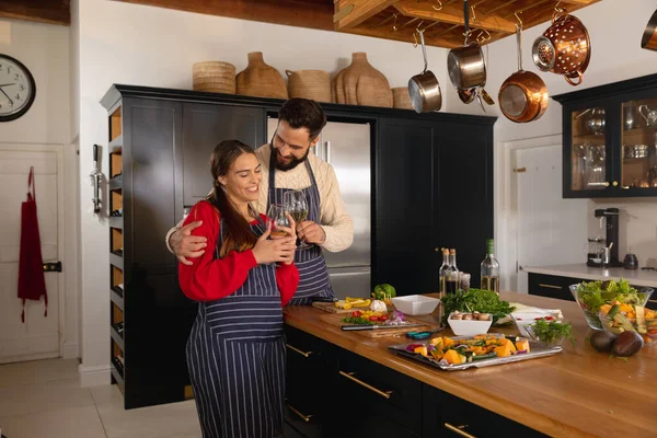 Glückliches Kaukasisches Paar Das Der Küche Essen Zubereitet Weißweingläser Umarmt — Stockfoto