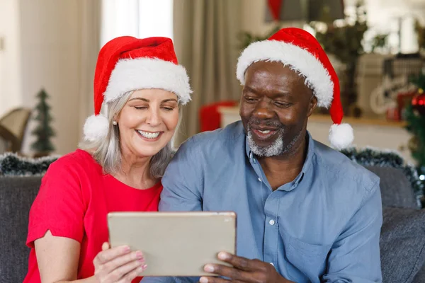 Šťastný Seniorský Pár Santa Klobouky Pomocí Tabletu Trávit Kvalitní Čas — Stock fotografie