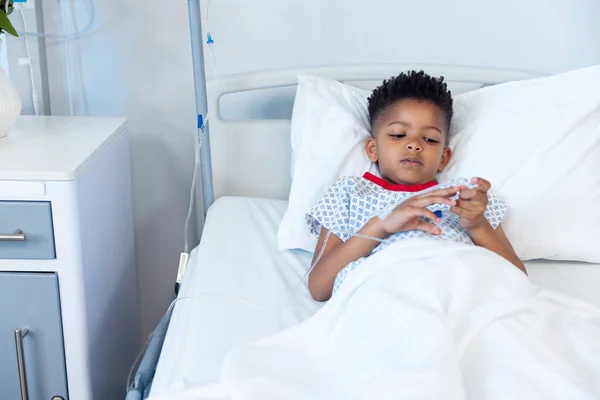アフリカ系アメリカ人の少年が点滴で コピースペースのある病院のベッドに横たわっています 医療サービス — ストック写真
