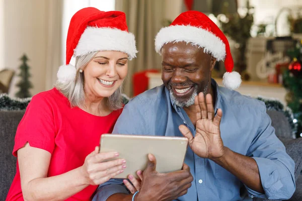 快乐的长大成人夫妇 戴着圣诞礼帽 带着平板电脑 在圣诞节和退休观念上花费高质量的时间 — 图库照片