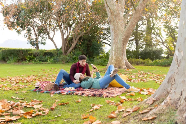 Szczęśliwa Para Birasowa Piknik Dywanie Przy Użyciu Smartfona Jesiennym Ogrodzie — Zdjęcie stockowe