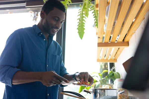 幸せなアフリカ系アメリカ人の男がキッチンや料理の夕食に立っている 自宅だけで質の高い時間を過ごす — ストック写真