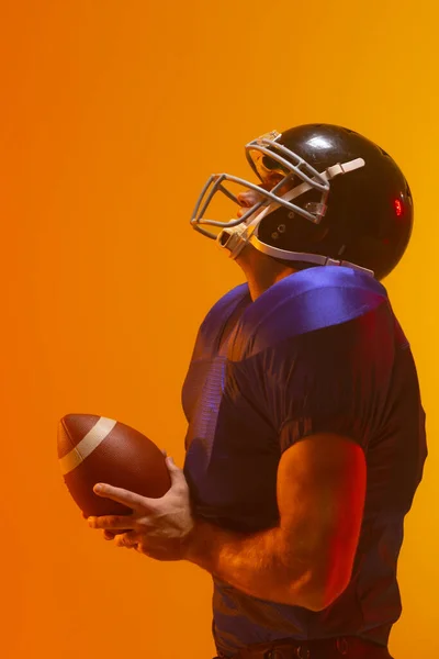 ネオンオレンジの照明でボールを保持白人男性アメリカ人サッカー選手 スポーツ トレーニング アクティブなライフスタイルの概念 — ストック写真