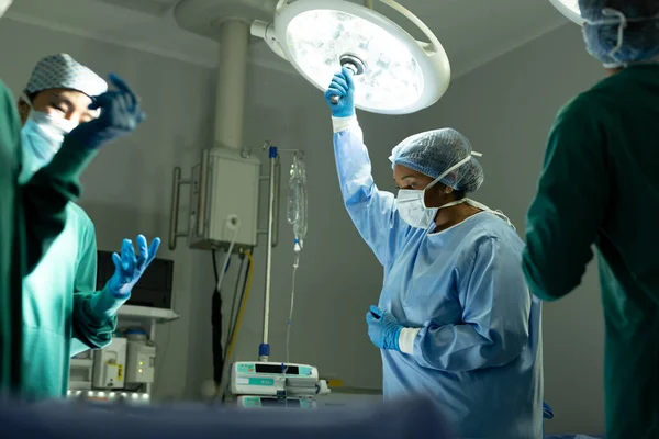 Tecnologia Cirúrgica Feminina Biracial Ajustando Luz Teatro Operações Durante Operação — Fotografia de Stock