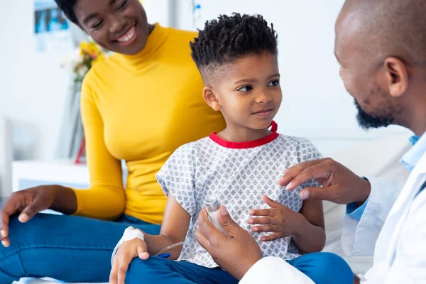 非裔美国男性医生解释吸入器给男孩患者 与母亲住院 医疗和保健服务 — 图库照片