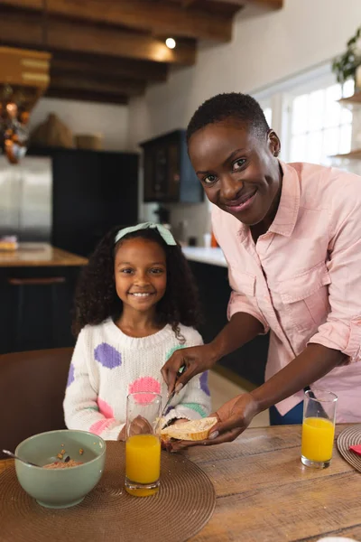 母と朝食を食べる幸せなアフリカ系アメリカ人の少女の垂直画像 家族と一緒に質の高い時間を過ごすコンセプト — ストック写真