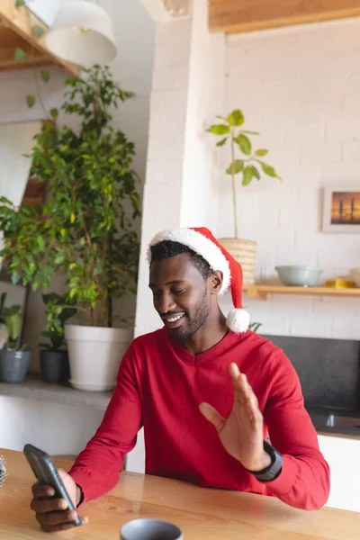 모자를 스마트폰으로 비디오 통화하는 아프리카 미국인 크리스마스에 집에서 시간을 보내는 — 스톡 사진