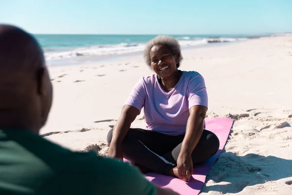 快乐的非洲裔美国老年妇女一边和男人聊天 一边在沙滩上放松地躺在垫子上 复制空间 度假和积极的生活方式 — 图库照片
