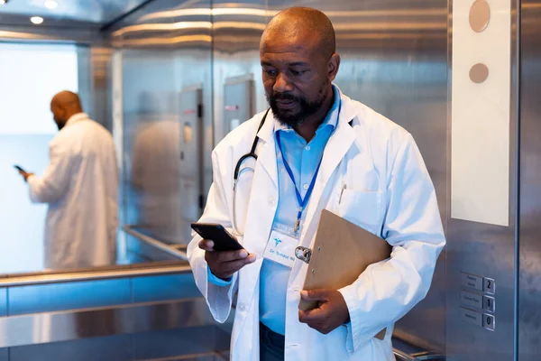 Médico Afroamericano Mirando Teléfono Inteligente Ascensor Del Hospital Servicios Hospitalarios — Foto de Stock