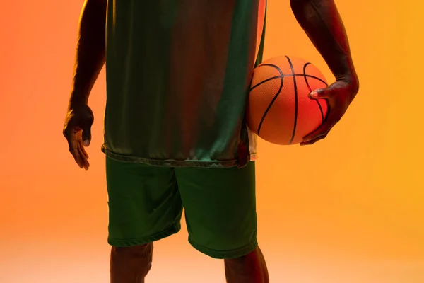 Зображення Середньої Секції Афроамериканського Баскетболу Баскетболом Неоновому Помаранчевому Фоні Спорт — стокове фото