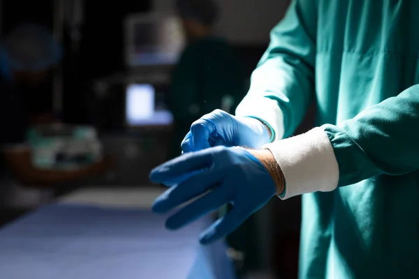 外科医生在黑暗手术室戴手套的中段 有复制空间 医疗和保健服务 — 图库照片