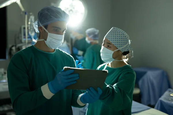 Ameliyat Sırasında Ameliyathanede Tablet Kullanan Çeşitli Kadın Erkek Cerrahlar Tartışılıyor — Stok fotoğraf