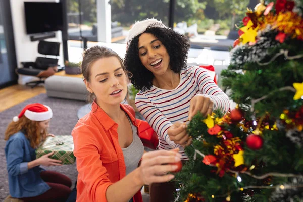 クリスマスツリーを飾るサンタの帽子と幸せな多様な友人 クリスマス お祝い 包容力とライフスタイルの概念 — ストック写真