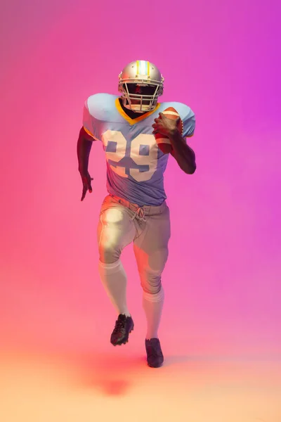 Amerykański Amerykański Futbolista Trzymający Piłkę Neonowym Różowym Oświetleniem Sport Ruch — Zdjęcie stockowe