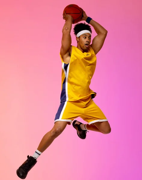 图片显示的是一个身披粉红球衣的篮球运动员在空中跳跃的情景 体育和竞争概念 — 图库照片