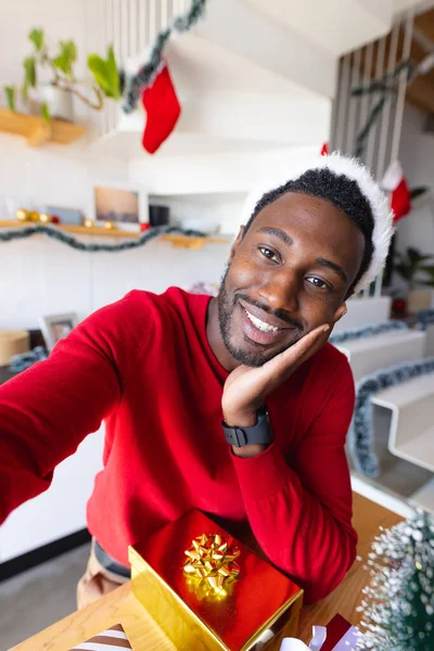 サンタの帽子をかぶってビデオ通話をしている幸せなアフリカ系アメリカ人男性 クリスマスだけで家で質の高い時間を過ごす — ストック写真