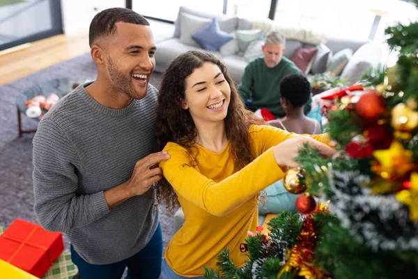 照片上 一对快乐的 多样化的夫妇在家里装饰圣诞树 庆祝圣诞节 圣诞节 庆祝活动 包容和生活方式概念 — 图库照片