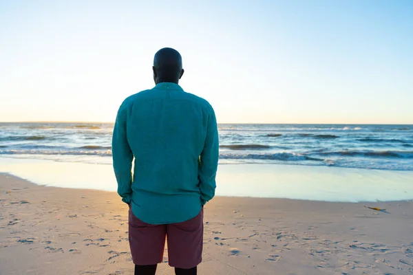Вид Сзади Африканского Старшеклассника Смотрящего Море Ясным Небом Стоящего Пляже — стоковое фото
