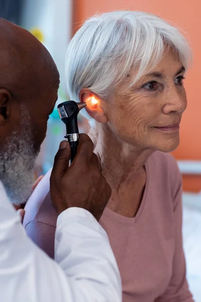 高齢女性患者の耳に聴診器を使用して多様な高齢男性医師の垂直 コピースペース 医療サービス — ストック写真
