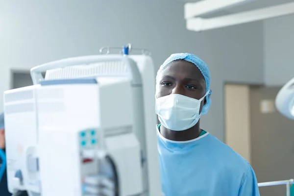 아프리카 미국인 의사가 컴퓨터 장비를 사용하여 수술실에서 복제품 공간을 사용하는 — 스톡 사진