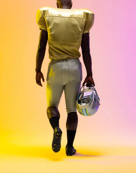 Amerykański Amerykański Piłkarz Trzymający Kask Neonowym Żółtym Fioletowym Oświetleniem Sport — Zdjęcie stockowe