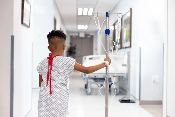コピースペース付きの病院で点滴スタンドで歩くアフリカ系アメリカ人少年患者の背面図 医療サービス — ストック写真
