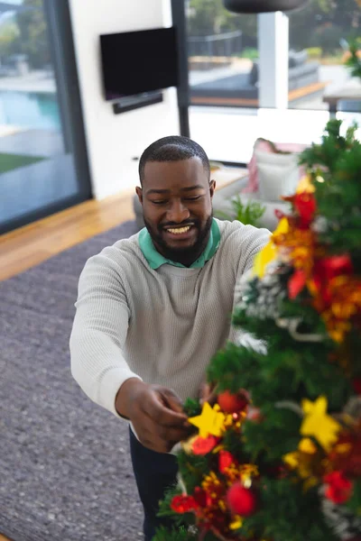 Χαρούμενος Αφροαμερικάνος Που Στολίζει Χριστουγεννιάτικο Δέντρο Στο Σαλόνι Περνάμε Ποιοτικό — Φωτογραφία Αρχείου