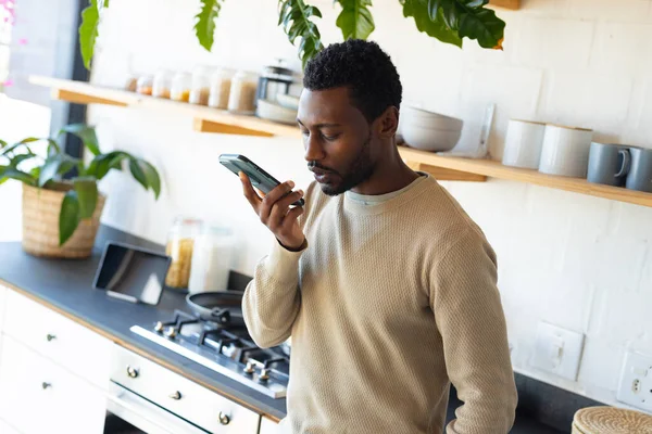 Szczęśliwy Afrykański Amerykanin Opierający Się Blat Kuchni Rozmawiający Przez Smartfona — Zdjęcie stockowe