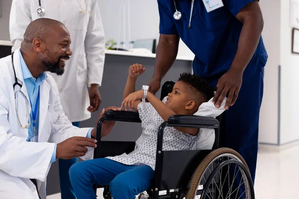 廊下で車椅子の少年と話すアフリカ系アメリカ人男性医師の笑顔 医療サービス — ストック写真