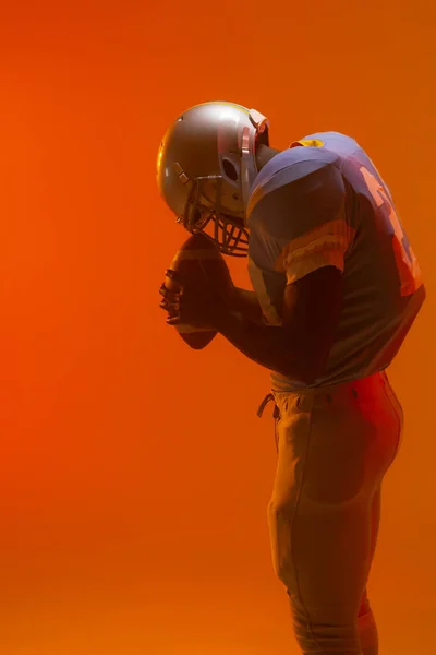Amerykański Amerykański Futbolista Trzymający Piłkę Neonowym Pomarańczowym Oświetleniem Sport Ruch — Zdjęcie stockowe