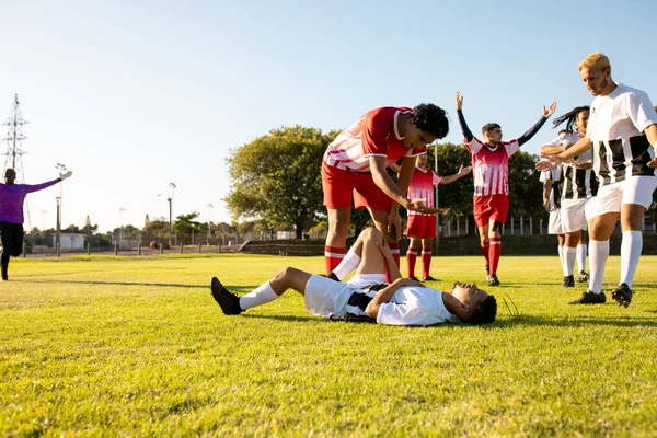 比赛期间 多种族的男足跑向受伤的球员 躺在草地上 复制空间 团体运动及比赛概念 — 图库照片