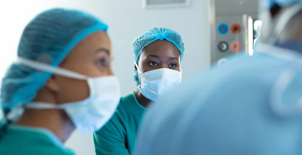 手術中に劇場で同僚と話す2人の多様な女性外科医 コピースペースと 医療サービス — ストック写真