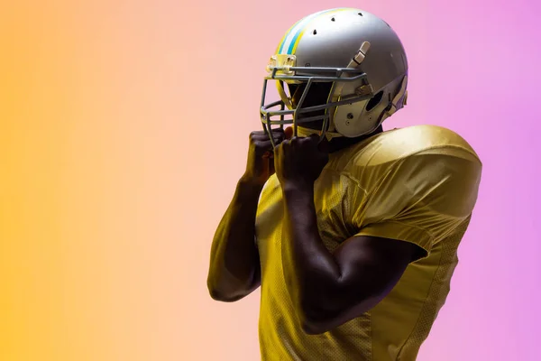Africký Americký Fotbalista Nosí Helmu Neonově Žlutým Fialovým Osvětlením Sport — Stock fotografie