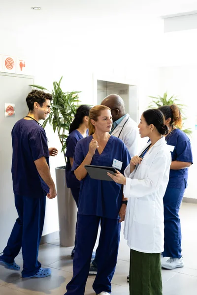 Vertikal Två Olika Kvinnliga Läkare Med Tablett Talar Upptagen Sjukhuskorridor — Stockfoto