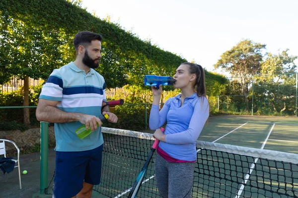 白种人夫妇在室外网球场打网球 聊天和喝水 健康爱好 健身和闲暇时间概念 — 图库照片