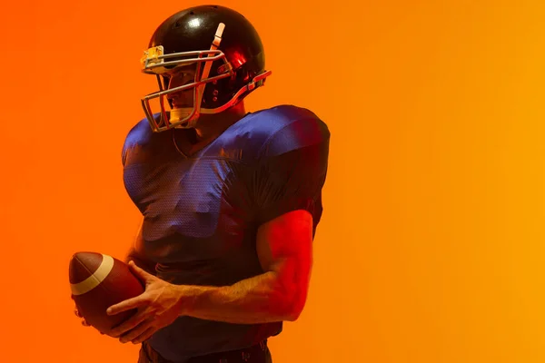 Biały Mężczyzna Amerykański Piłkarz Trzymający Piłkę Neonowym Pomarańczowym Oświetleniem Sport — Zdjęcie stockowe