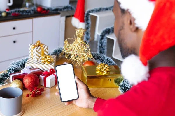 非洲裔美国人头戴桑塔帽 用智能手机与版权空间 圣诞时独自在家度过美好的时光 — 图库照片