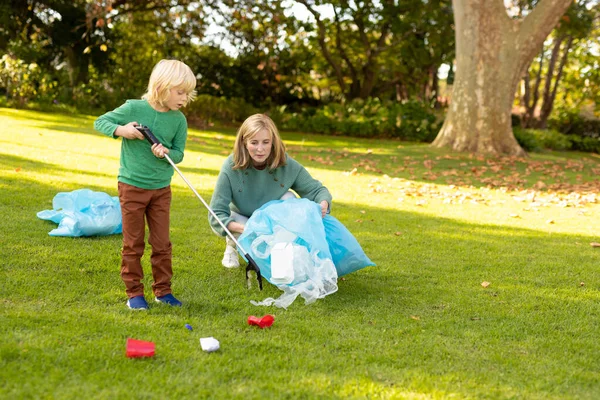 照片上是快乐的高加索祖母和孙子 他们带着垃圾袋在花园里 回收和生态意识概念 — 图库照片