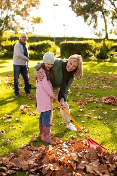 幸せな白人の祖母と孫娘が庭で葉をスワイプする垂直画像 家族と一緒に質の高い時間を過ごすコンセプト — ストック写真