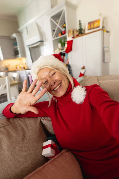 サンタの帽子をかぶった幸せなシニア白人女性は ビデオ通話をしています クリスマスだけで家で質の高い時間を過ごす — ストック写真