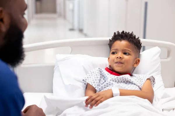 Afroamerikansk Manlig Läkare Pratar Med Pojkpatient Sjukhussäng Korridoren Med Kopieringsutrymme — Stockfoto