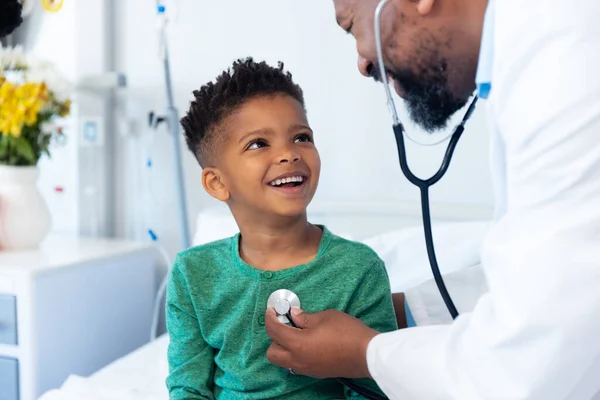 非洲裔美国男医生在医院用听诊器治疗面带微笑的男病人 医疗和保健服务 — 图库照片