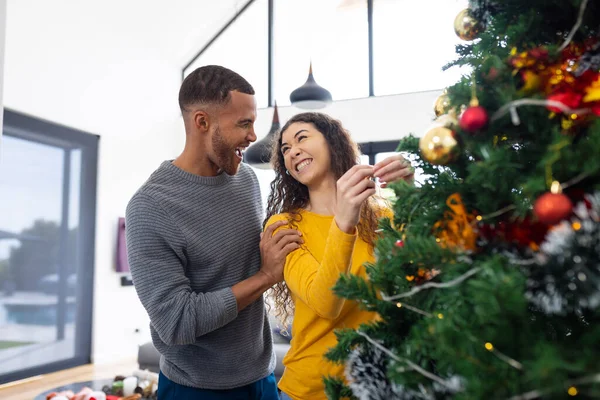 照片上 一对快乐的 多样化的夫妇在家里装饰圣诞树 庆祝圣诞节 圣诞节 庆祝活动 包容和生活方式概念 — 图库照片