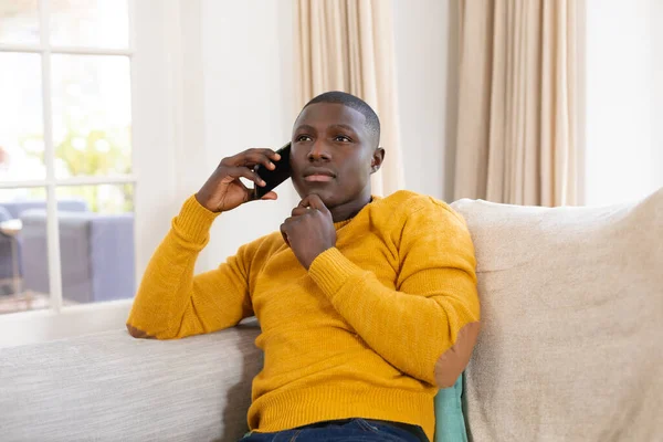Tankeväckande Afrikansk Amerikansk Man Sitter Soffa Hemma Med Hjälp Smartphone — Stockfoto