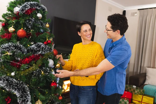 Caucasian couple spending time together decorating the christmas tree. Christmas, family time and celebration concept.