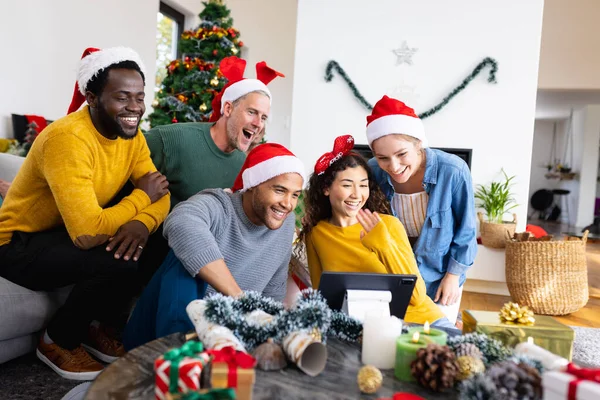 照片中快乐多样的朋友在家里庆祝圣诞节 制作平板电脑视频通话 圣诞节 庆祝活动 包容和生活方式概念 — 图库照片